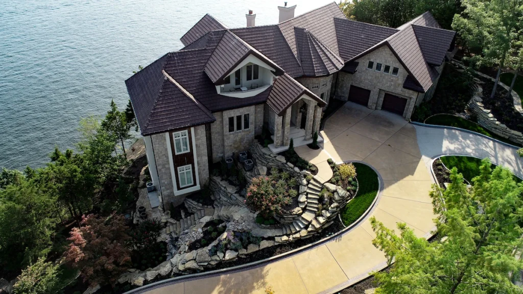 Aerial view of a lake front mansion with landscaped front yard.