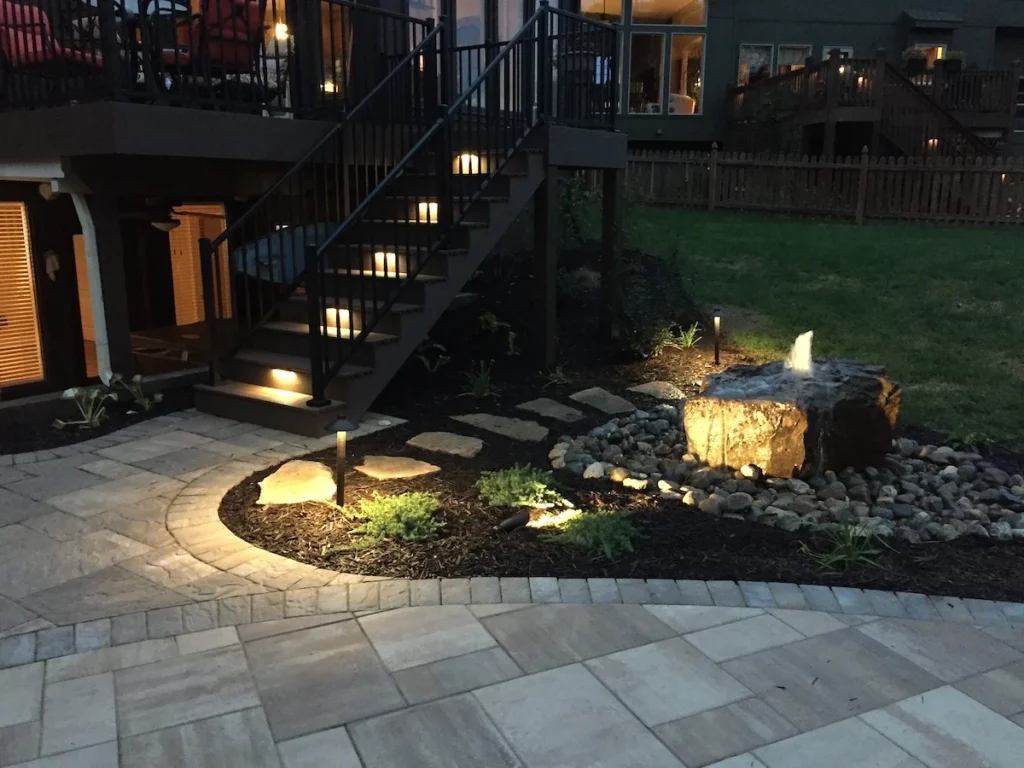 Backyard landscaping with lighting and a water feature.