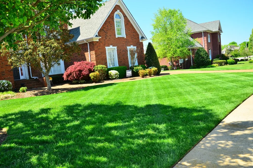 A brick house with a very green front lawn.