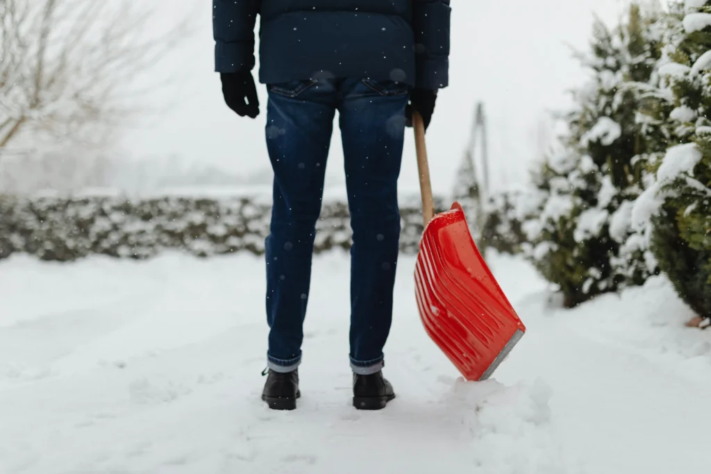 Someone holding a shovel outside in the snow.