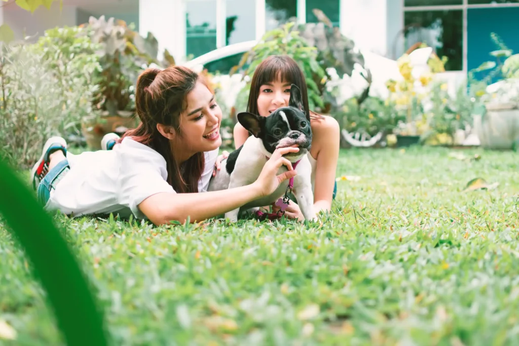 A mother, daughter and dog outside playing on the lawn.